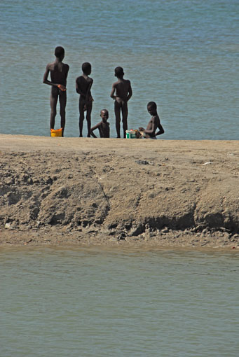 Boys standing on flooded salt ponds